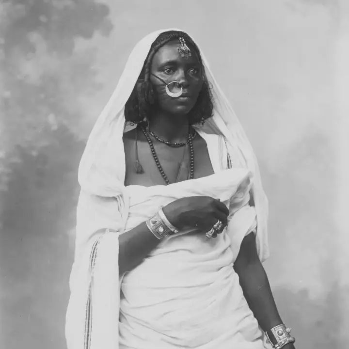 Comunidades Portrait of an African Woman dressed in traditional costume, wearing decorative jewelry.